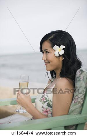 Picture - A woman holding wineglass at beach. Fotosearch