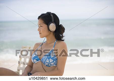 Stock Image - A woman listening to music at beach. Fotosearch