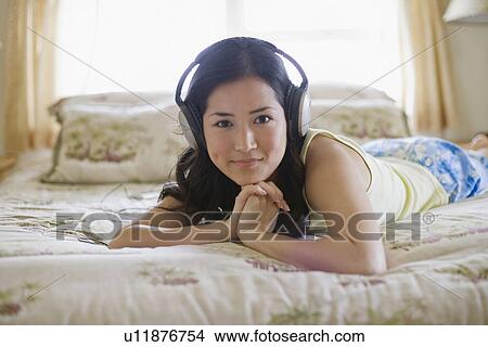 A woman listening to music on bed View Large Photo Image Picture - A woman listening to music on bed. Fotosearch