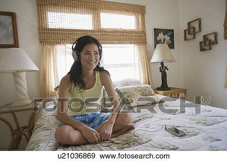 A woman listening to music on bed View Large Photo Image Stock Photo - A woman listening to music on bed. Fotosearch