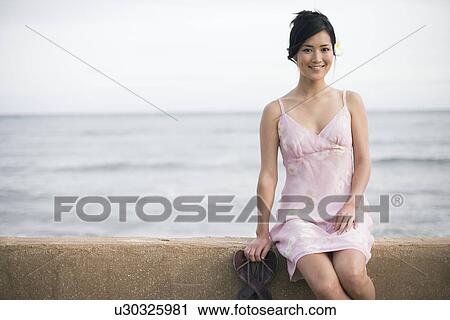 A woman sitting on wall by sea View Large Photo Image Stock Image - A woman sitting on wall by sea. Fotosearch