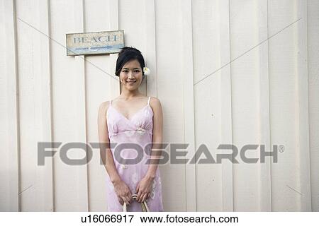 Stock Photo - A woman standing by wall. Fotosearch