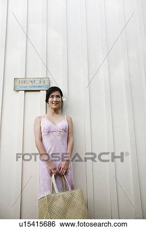 Stock Photograph - A woman standing by wall. Fotosearch