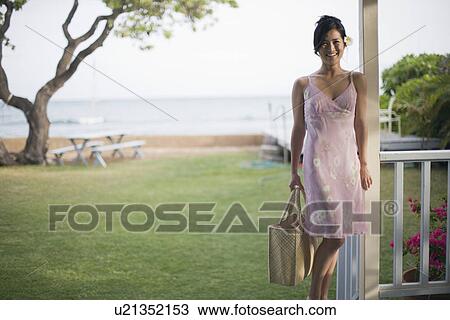 Stock Image - A woman with bag smiling on balcony. Fotosearch