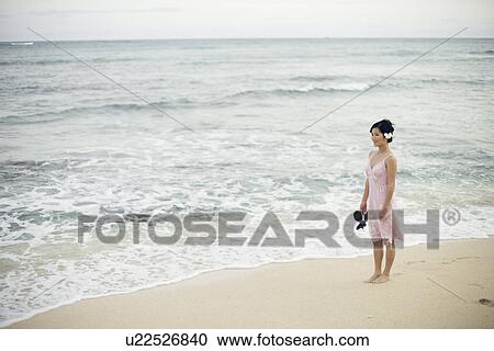View of a woman standing on beach View Large Photo Image Stock Image - View of a woman standing on beach. Fotosearch