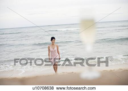 Stock Photo - View of a woman walking on beach. Fotosearch