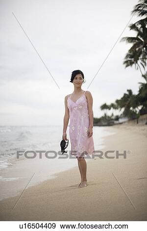 Stock Photo - View of a young woman standing on beach. Fotosearch