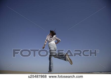 Stock Photo - Low angle view of a young woman running. Fotosearch