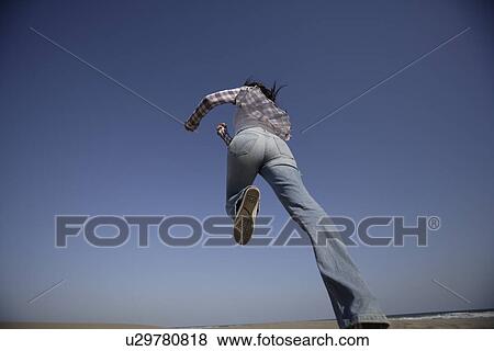 Stock Photo - Low angle view of a young woman running. Fotosearch