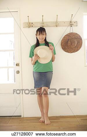 Stock Photo - Portrait of a smiling woman holding hat. Fotosearch