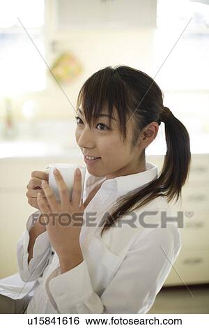 Stock Photograph - View of a cheerful woman holding cup. Fotosearch