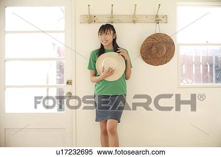 Stock Photography - View of a smiling woman holding hat. Fotosearch
