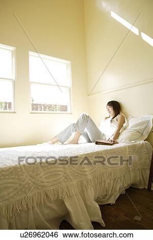 Stock Photograph - View of a woman lying on bed. Fotosearch