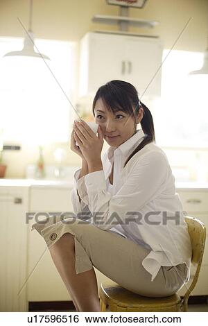 Stock Photograph - View of a woman sitting on chair. Fotosearch