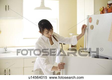 View of a young woman opening refrigerator in kitchen View Large Photo Image Stock Photography - View of a young woman opening refrigerator in kitchen. Fotosearch