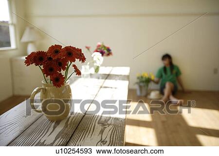 Stock Image - Woman with flowerpot in foreground. Fotosearch