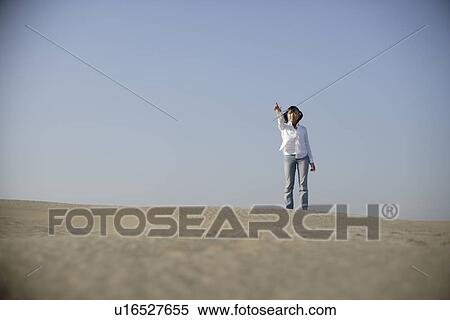 Stock Photography - Young woman standing alone in desert. Fotosearch