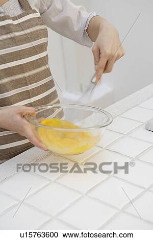 Stock Image - Close-up of hands mixing egg yolk with whisk. Fotosearch