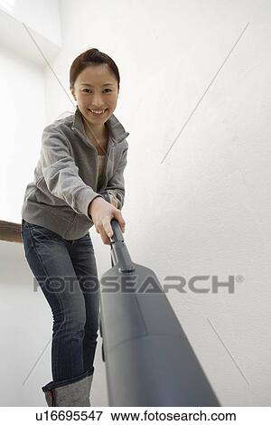 Stock Photo - Portrait of a young woman cleaning with a vacuum cleaner. Fotosearch