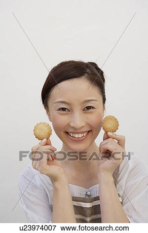 Portrait of a young woman holding biscuits View Large Photo Image Stock Photo - Portrait of a young woman holding biscuits. Fotosearch
