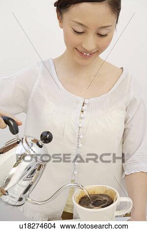 Picture - View of a woman pouring water in a cup. Fotosearch