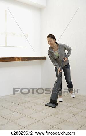 View of a young woman cleaning floor with a vacuum cleaner View Large Photo Image Stock Image - View of a young woman cleaning floor with a vacuum cleaner. Fotosearch