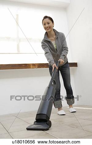 View of a young woman cleaning floor with a vacuum cleaner View Large Photo Image Stock Photograph - View of a young woman cleaning floor with a vacuum cleaner. Fotosearch