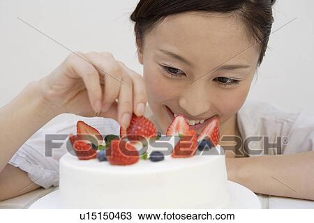 Stock Image - View of a young woman garnishing a pastry. Fotosearch