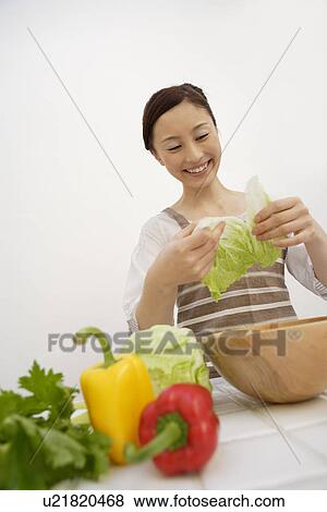 Stock Photo - View of a young woman holding tearing lettuce. Fotosearch