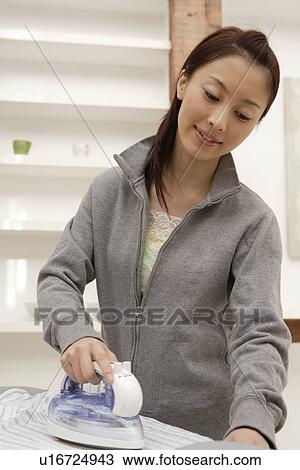 View of a young woman ironing a shirt View Large Photo Image Stock Image - View of a young woman ironing a shirt. Fotosearch