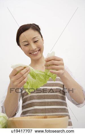 Stock Photo - View of a young woman tearing lettuce. Fotosearch