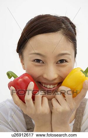 Stock Photo - View of a young woman with bell peppers in her hand. Fotosearch