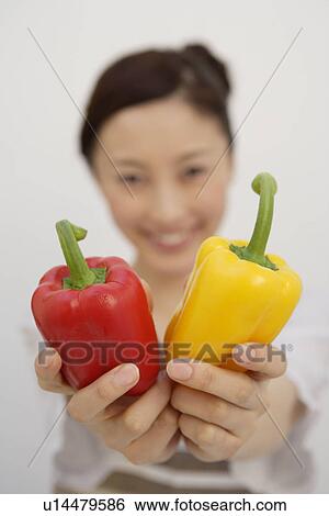 Stock Photograph - View of a young woman with bell peppers in her hands. Fotosearch