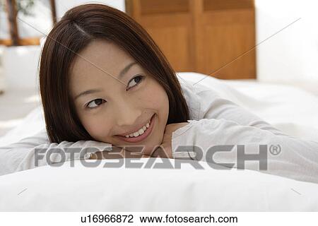 Stock Image - A young woman lying on a bed. Fotosearch