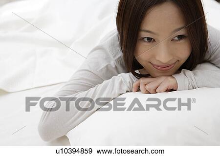 Stock Photo - A young woman lying on a bed. Fotosearch