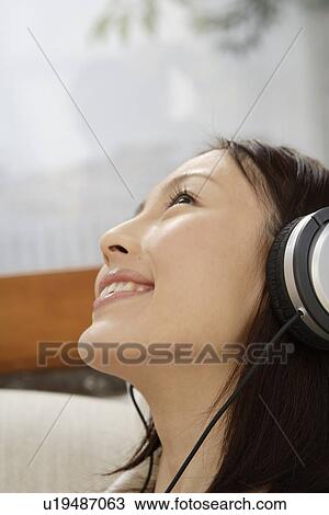 Stock Image - Close-up of a young woman using a headphone. Fotosearch