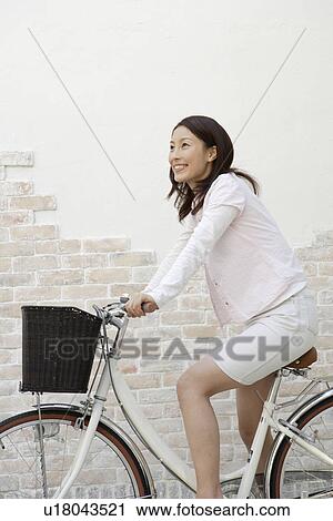 Side of a young woman sitting on a bicycle View Large Photo Image Stock Image - Side of a young woman sitting on a bicycle. Fotosearch