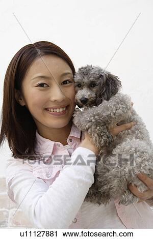 Stock Image - View of a young woman holding a dog. Fotosearch