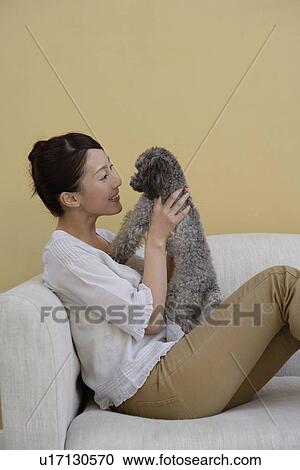 Stock Image - View of a young woman holding a dog. Fotosearch
