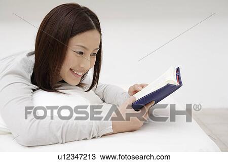 View of a young woman reading a book View Large Photo Image Stock Image - View of a young woman reading a book. Fotosearch