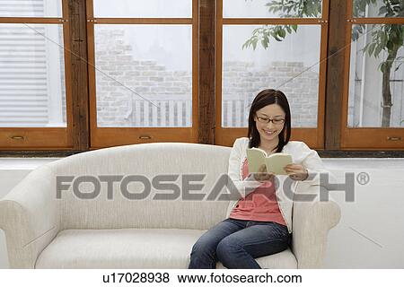 Stock Photo - View of a young woman reading a book. Fotosearch