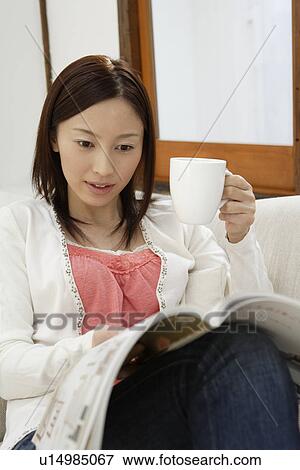 Stock Photo - View of a young woman reading a magazine. Fotosearch