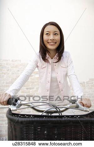 Stock Photo - View of a young woman sitting on a bicycle. Fotosearch