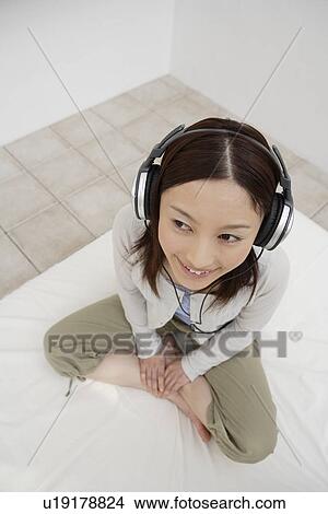Picture - View of a young woman using a headphone. Fotosearch