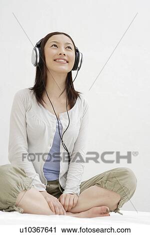 View of a young woman using a headphone View Large Photo Image Stock Image - View of a young woman using a headphone. Fotosearch