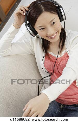 View of a young woman using a headphone View Large Photo Image Stock Image - View of a young woman using a headphone. Fotosearch