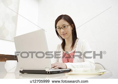 Stock Photo - View of a young woman using laptop. Fotosearch