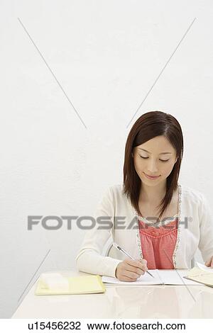 Stock Image - View of a young woman writing. Fotosearch