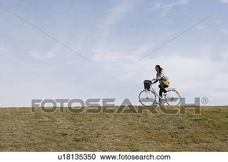 Stock Image - A young woman riding a bicycle. Fotosearch