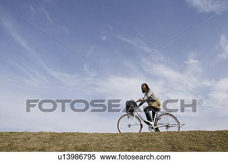 A young woman riding a bicycle View Large Photo Image Stock Photography - A young woman riding a bicycle. Fotosearch